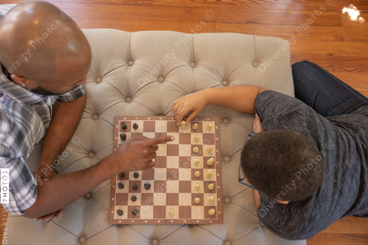 Black father and son playing chess together