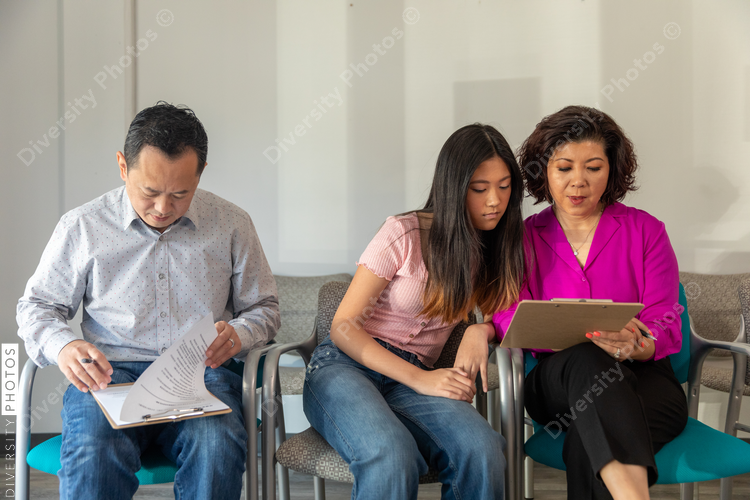 Chinese family waits in doctors office lobby completing translated forms