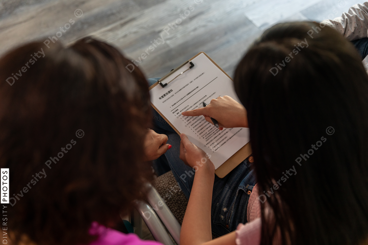 Asian girl completes translated healthcare documents for parents at medical office