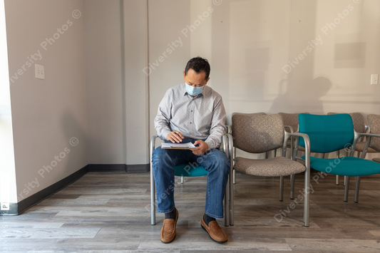 Asian man filling out patient forms at doctors office waiting area