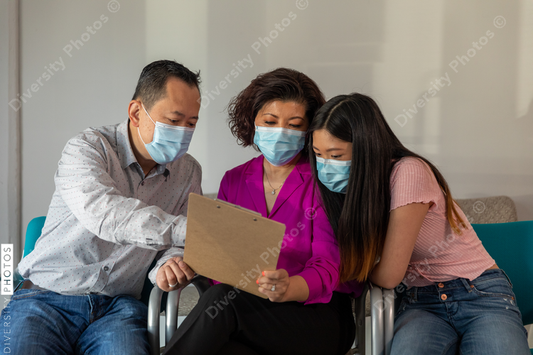 Asian family reviewing translated medical patient forms at doctors office
