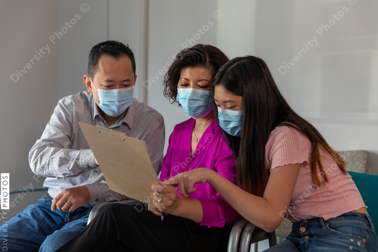 Asian family reviewing translated medical patient forms at doctors office