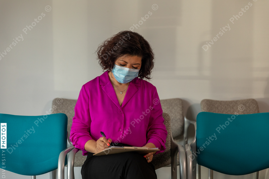 Asian woman completes patient forms in doctors lobby waiting room