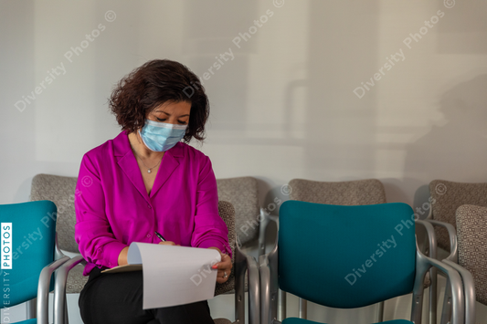 Asian woman completes patient forms in doctors lobby waiting room
