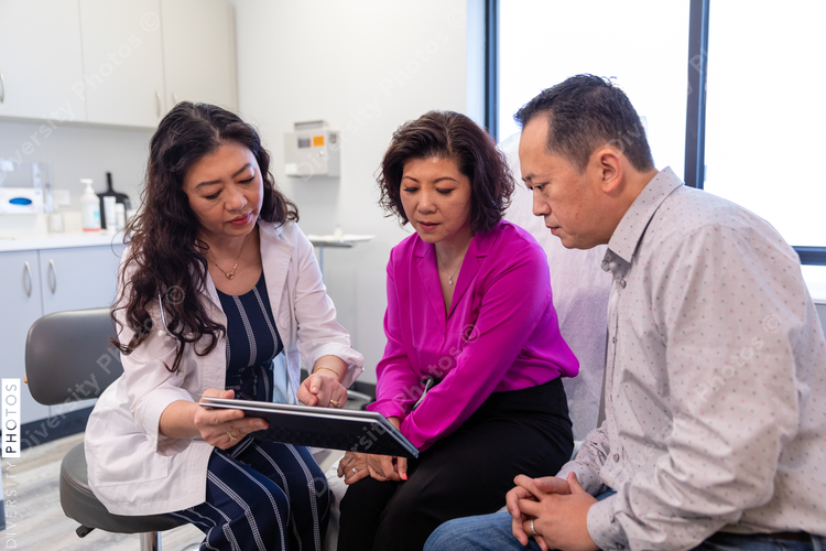 Asian doctor consulting patients in medical exam room