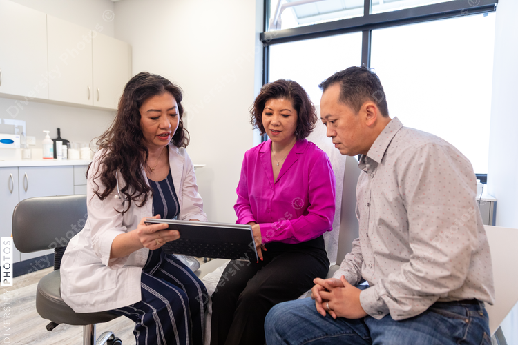 Asian doctor consulting patients in medical exam room