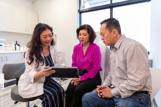 Asian doctor consulting patients in medical exam room
