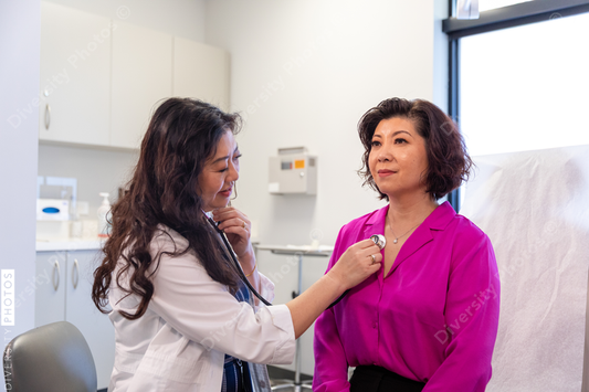 Asian doctor checks patient heartbeat using stethoscope