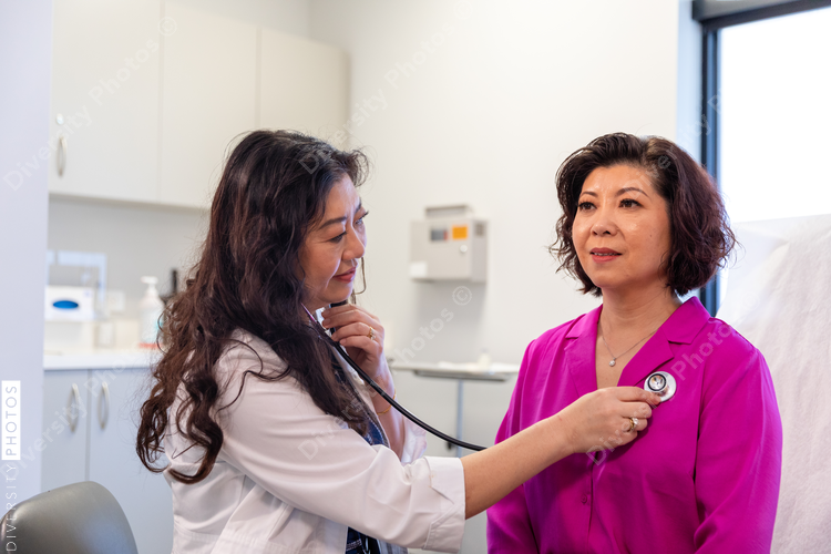 Asian doctor checks patient heartbeat using stethoscope