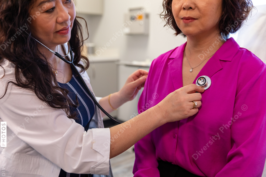 Asian doctor checks patient heartbeat using stethoscope