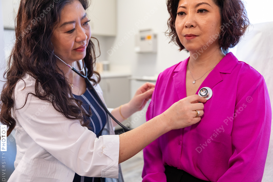 Asian doctor checks patient heartbeat using stethoscope