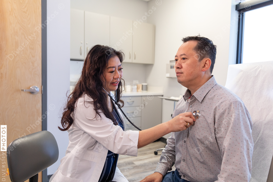 Asian doctor checks patient heartbeat using stethoscope