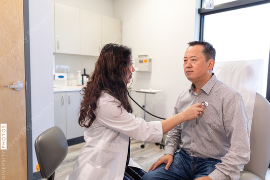 Asian doctor checks patient heartbeat using stethoscope