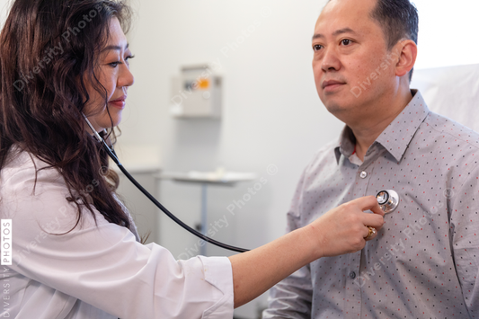 Asian doctor checks patient heartbeat using stethoscope