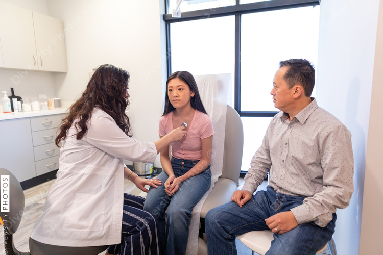 Asian doctor checks patient heartbeat using stethoscope