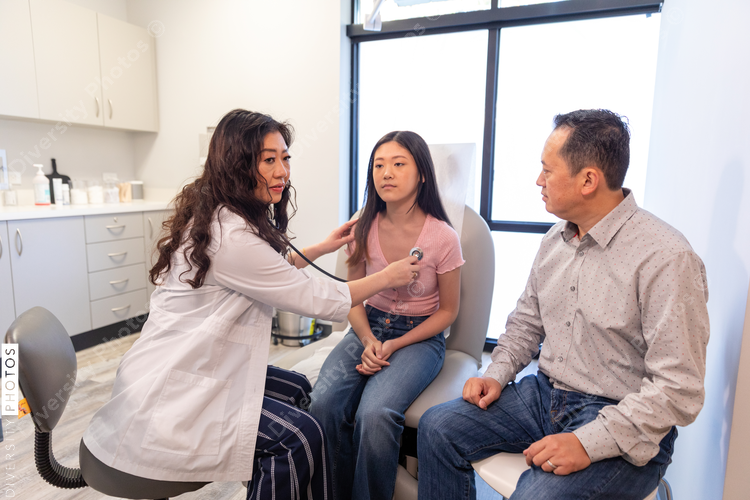 Asian doctor checks patient heartbeat using stethoscope