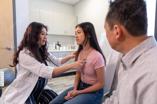 Asian doctor checks patient heartbeat using stethoscope