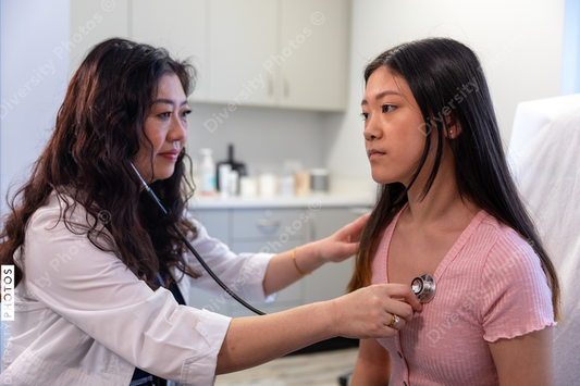 Asian doctor checks patient heartbeat using stethoscope