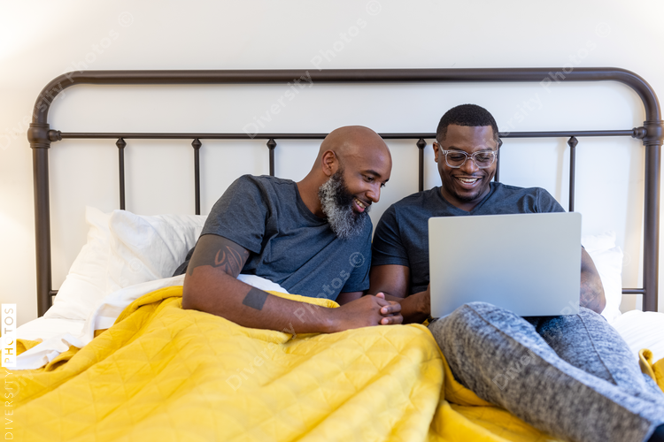 Black gay couple working in bed together, at home remotely