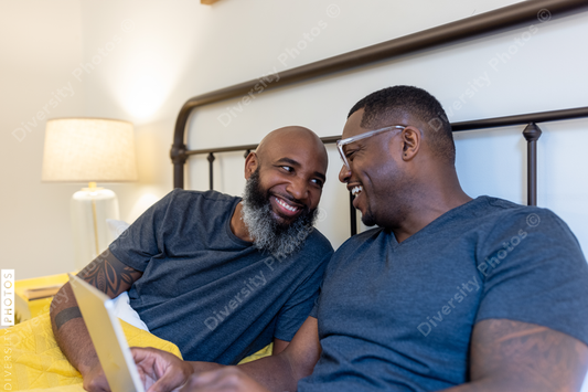 Black gay couple working in bed together, at home remotely
