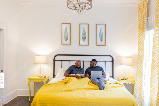 Black same gender couple working and reading in bed