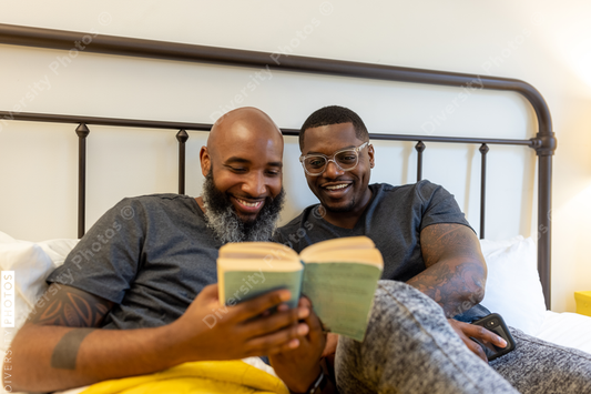 African American gay couple working and reading in bed at home, LGBTQ love