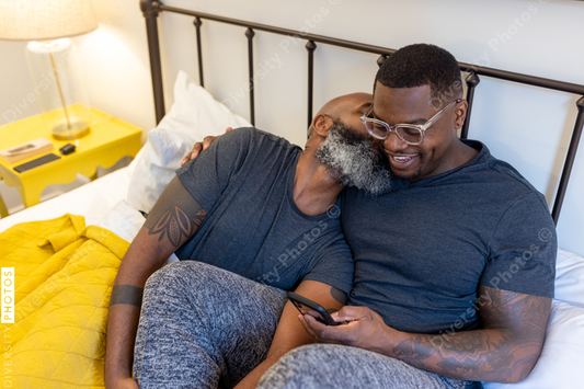 African American gay couple cuddling in bed at home, love is love connection