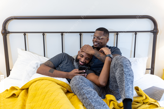 African American gay couple cuddling in bed at home, love is love connection