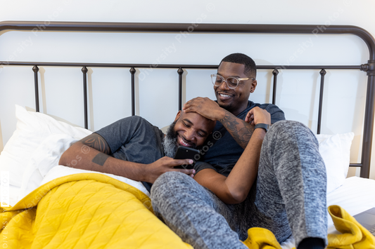 African American gay couple cuddling in bed at home, love is love connection