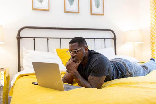 Black man working from home on laptop in bed