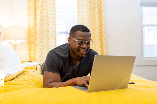 Black man working from home on laptop in bed