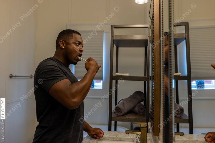 Black man brushes teeth in bathroom