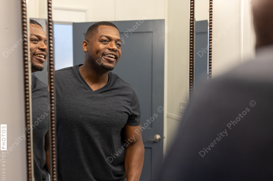 Black man checking reflection in mirror at home