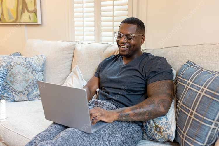 African American man working from home on laptop in living room, video chat conference call