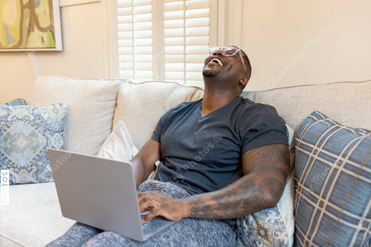 African American man working from home on laptop in living room, video chat conference call