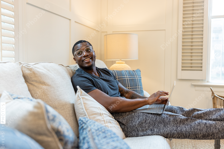 African American man working from home on laptop in living room, video chat conference call