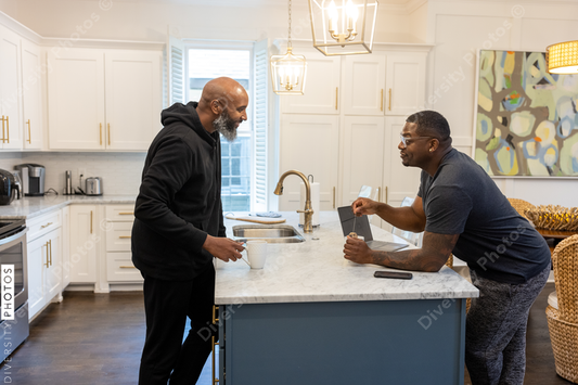 Black same sex couple drinking tea in kitchen at home