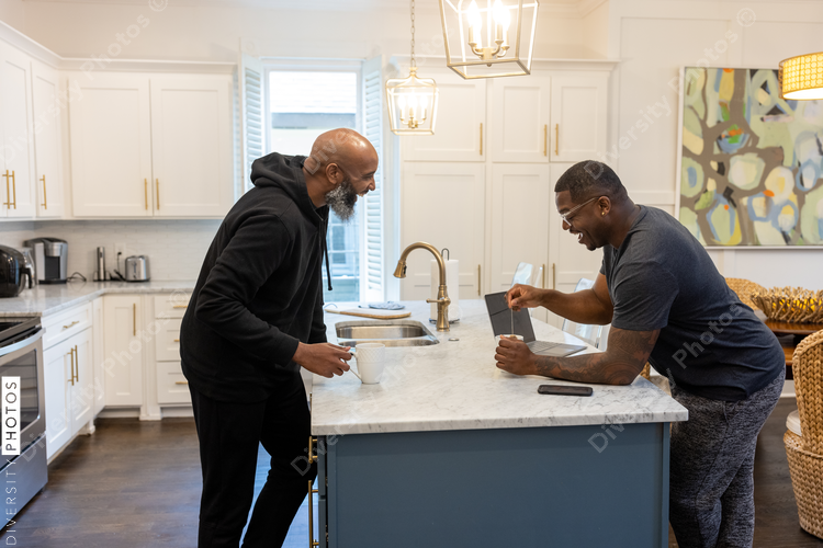 Black same sex couple drinking tea in kitchen at home