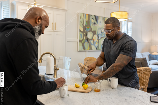 Black same sex couple drinking tea in kitchen at home