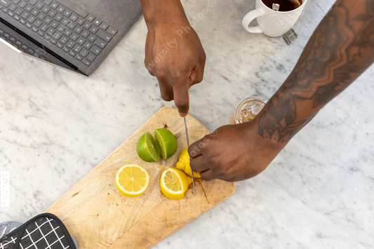 Black man with tattoos slices fruit for tea drink