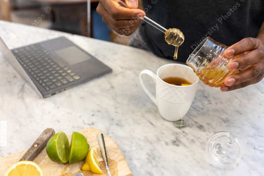 Black man adds honey sweetener to tea drink