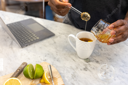 Black man adds honey sweetener to tea drink