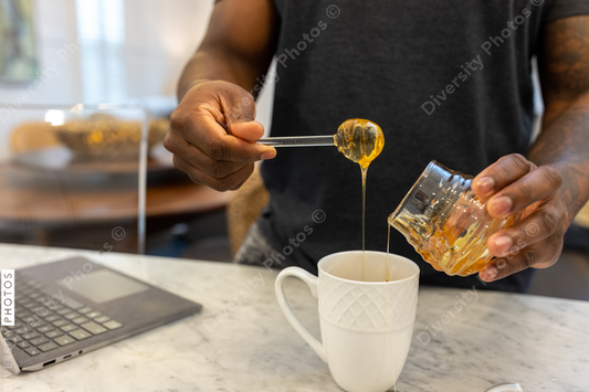 Black man adds honey sweetener to tea drink