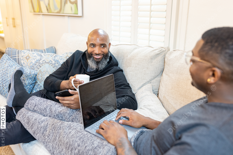 Black gay men have conversations on couch at home