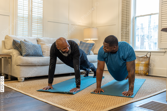 Black gay couple doing yoga exercises at home together, healthy lifestyle