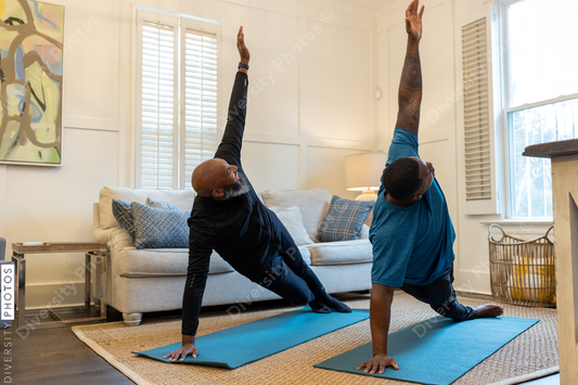 Black gay couple doing yoga exercises at home together, healthy lifestyle