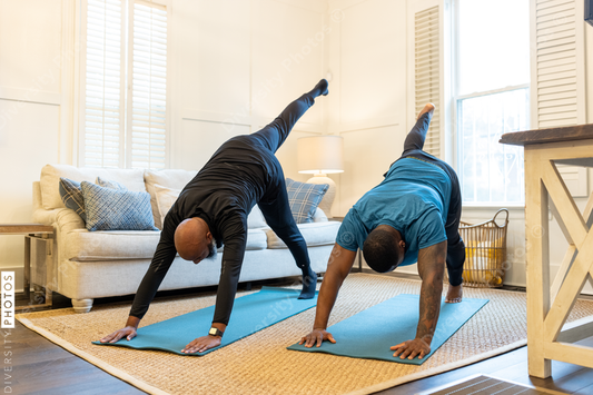 Black gay couple doing yoga exercises at home together, healthy lifestyle