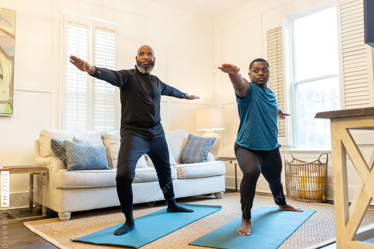 Black gay couple doing yoga exercises at home together, healthy lifestyle