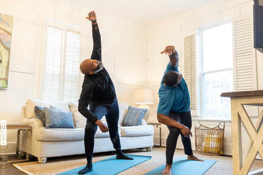 Black gay couple doing yoga exercises at home together, healthy lifestyle