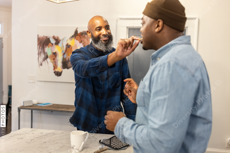 Black gay couple in kitchen at home, playful moment, conversations